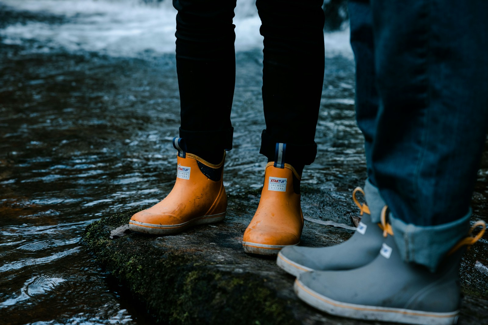 two people standing on a rock in the water